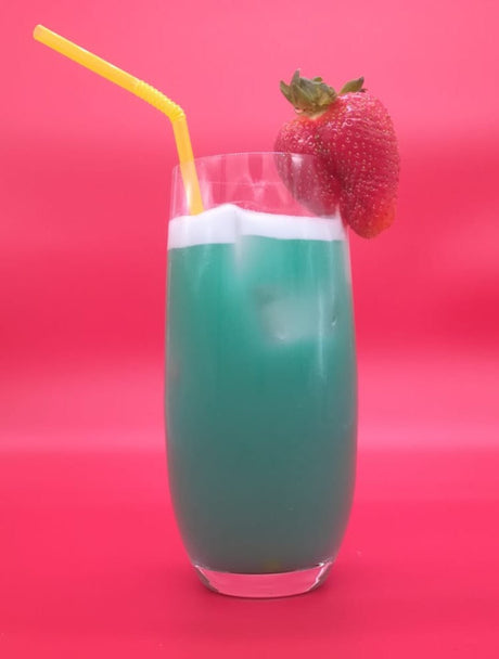 Türkisblauer Cocktail „Halluzination“ mit weißer Schaumkrone, gelbem Trinkhalm und Erdbeergarnitur vor pinkem Hintergrund.