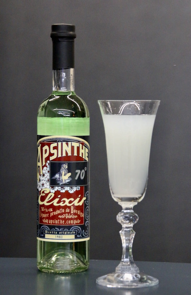 Grüne Flasche Apsinthe Elixir von Bordiga mit rotem Etikett und goldener Schrift, daneben ein klassisches Absinthglas mit trüber, milchiger Mischung aus Wasser und Absinth.