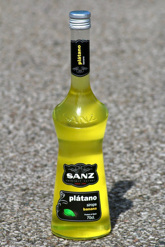 Flasche Sanz Plátano (Banane) Sirup, leuchtend gelber Sirup in 700 ml Flasche, schwarzes Etikett mit gelbem Schriftzug.