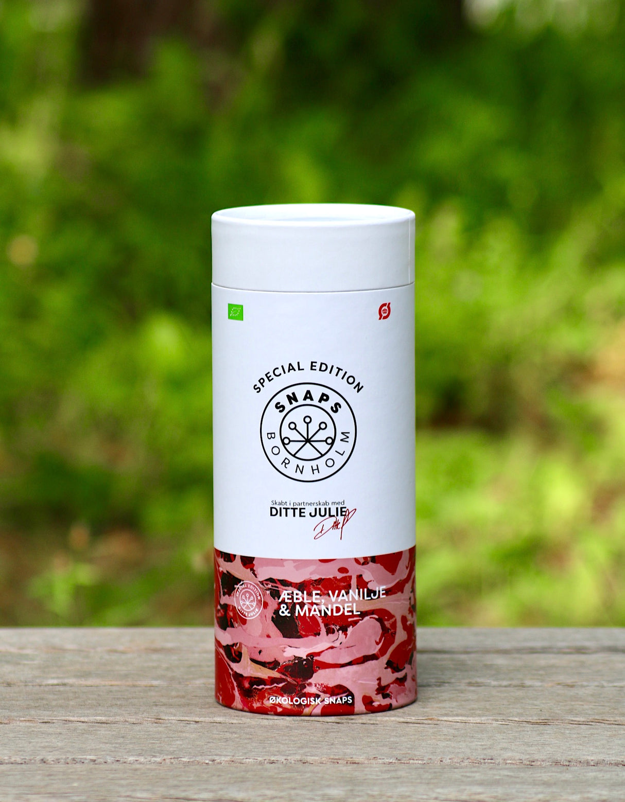 Geschenkbox des Bio-Schnapses von Bornholm, Apfel, Vanille, Mandel, auf Holzoberfläche vor unscharfem, grünem Hintergrund.