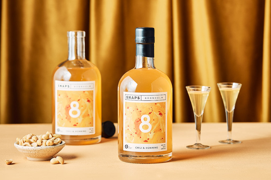 Bio Chili-Honig-Schnaps Bornholm 8, 50cl, dänischer Schnaps mit mild-würziger Note, serviert in Schnapsgläsern mit Erdnüssen.