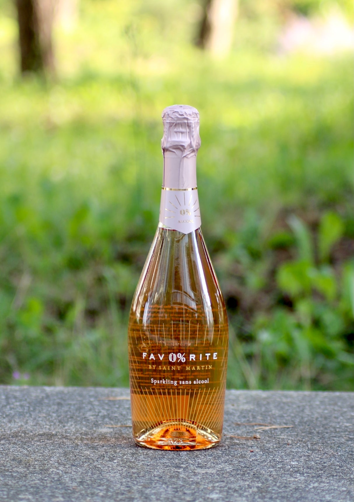 Fav0%rite Rosé alkoholfreier Schaumwein, Flasche auf Stein, unscharfer grüner Hintergrund