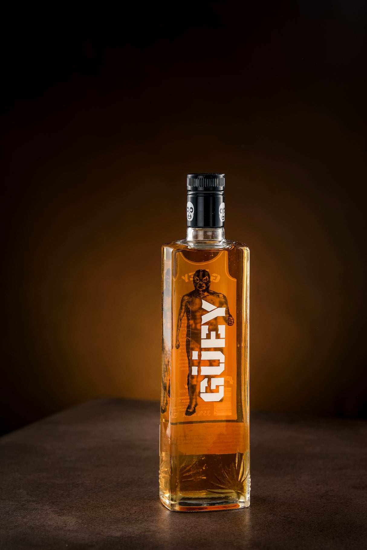 Goldener Tequila Güey in einer eleganten Flasche mit Lucha Libre-Design, präsentiert auf einem dunklen Hintergrund.