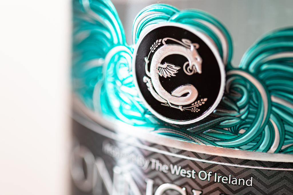 Detailaufnahme des Conncullin Irish Gin Etiketts mit türkisfarbenen Wellen und einem silbernen Symbol inspiriert vom Westen Irlands.