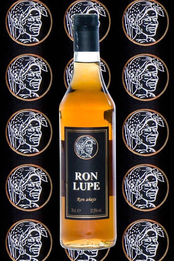 Rum Añejo Lupe, goldbraune Flasche mit schwarzem Etikett, vor dekorativem Hintergrund mit wiederholtem Logo der Marke.