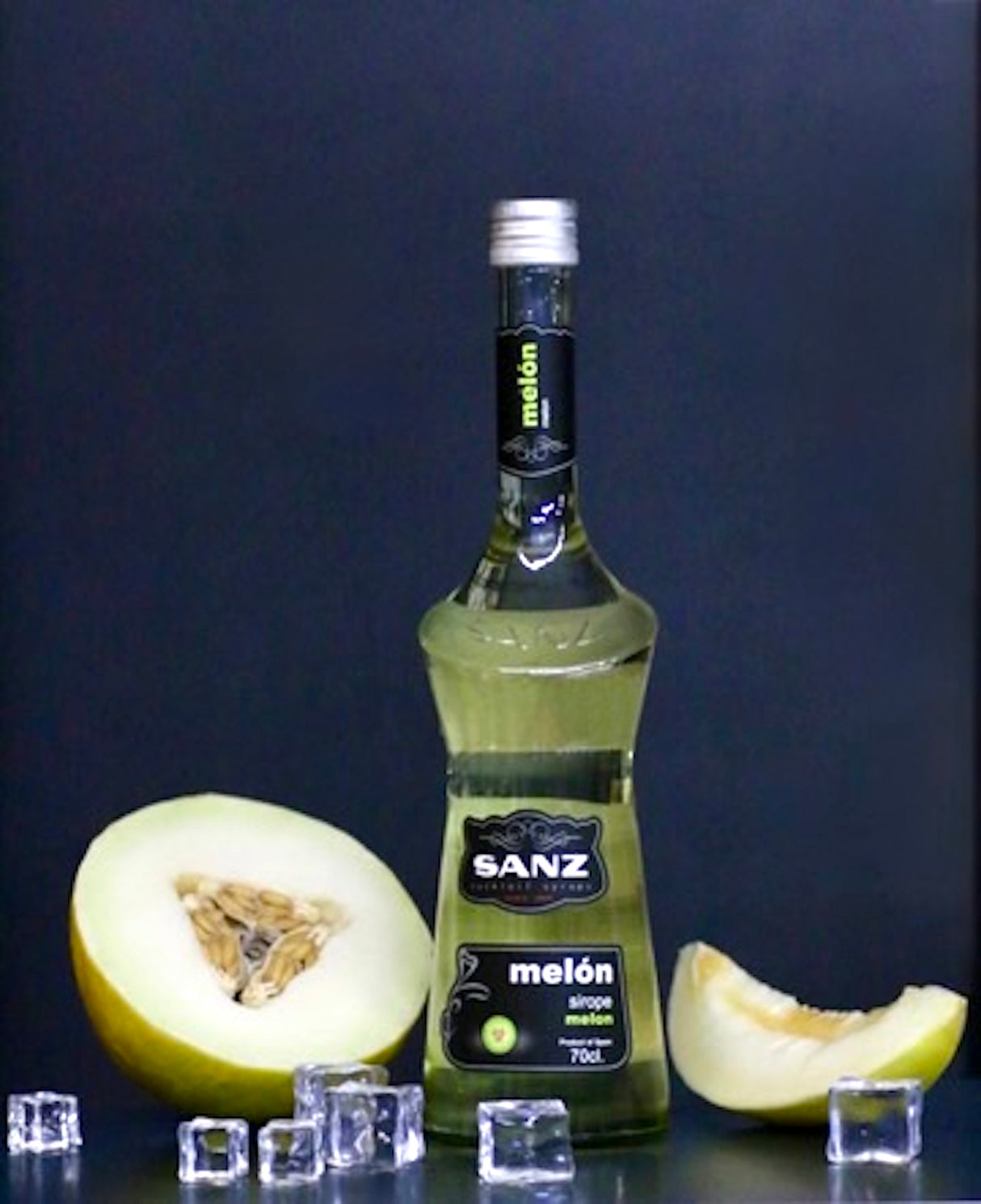 Melonensirup Sanz 700 ml, umgeben von gelben Melonenscheiben und Eiswürfeln vor schwarzem Hintergrund.
