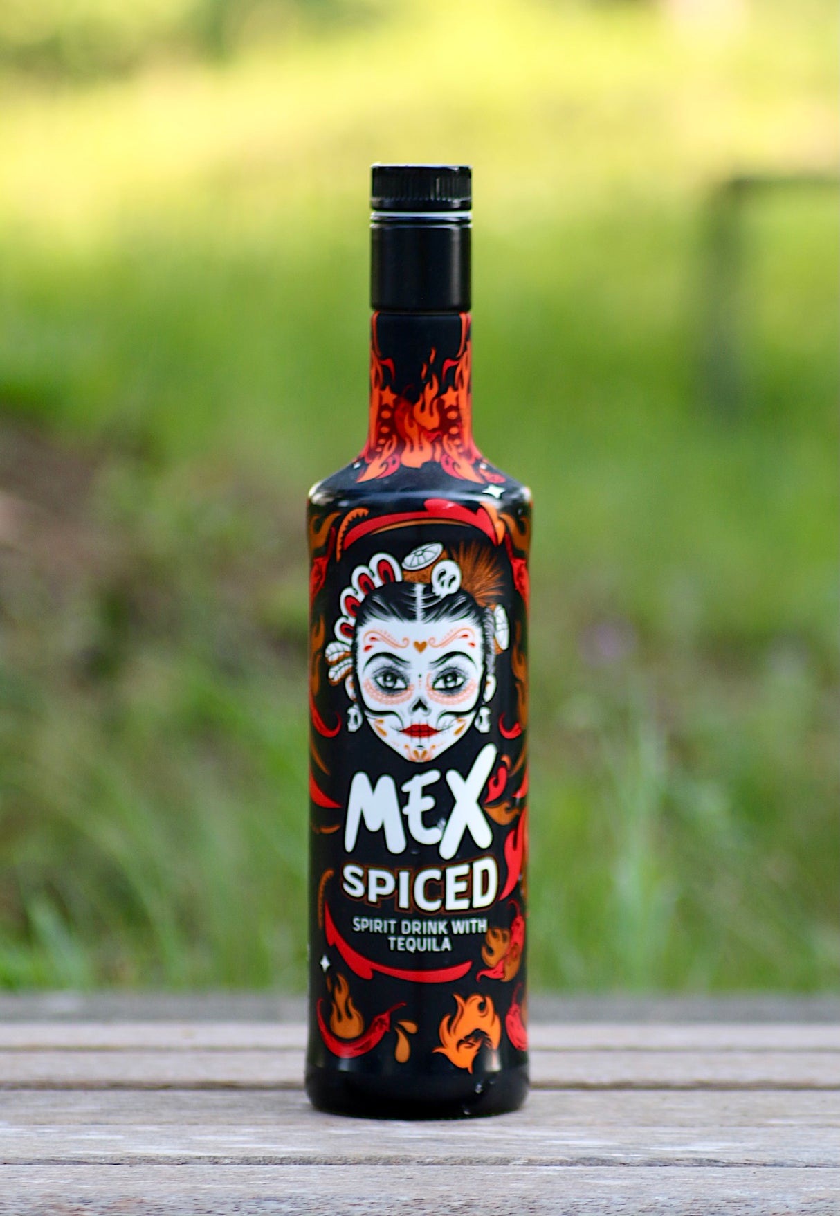 Alttext: Mex Spiced Tequila Spirituose mit Chili, Flasche mit feurigem Design und mexikanischem Totenkopf-Motiv.