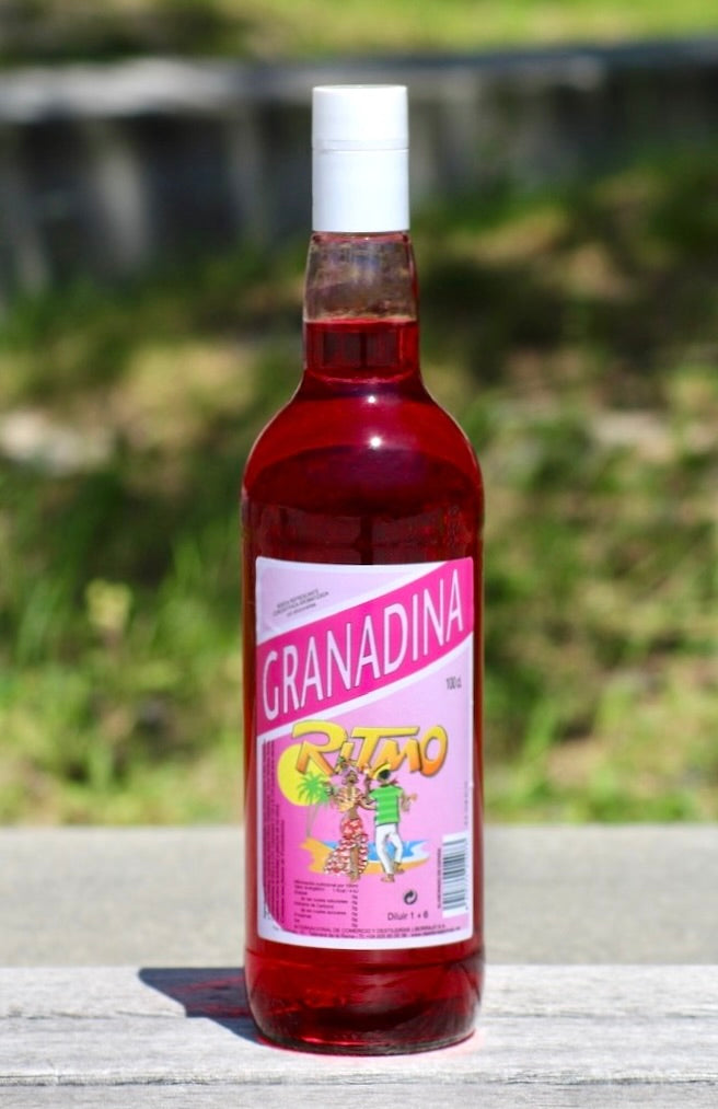 Flasche Ritmo Granadina ohne Zucker, 1 L, mit pinkfarbenem Etikett und tropischem Tanzmotiv, roter Sirup, weißer Schraubverschluss.