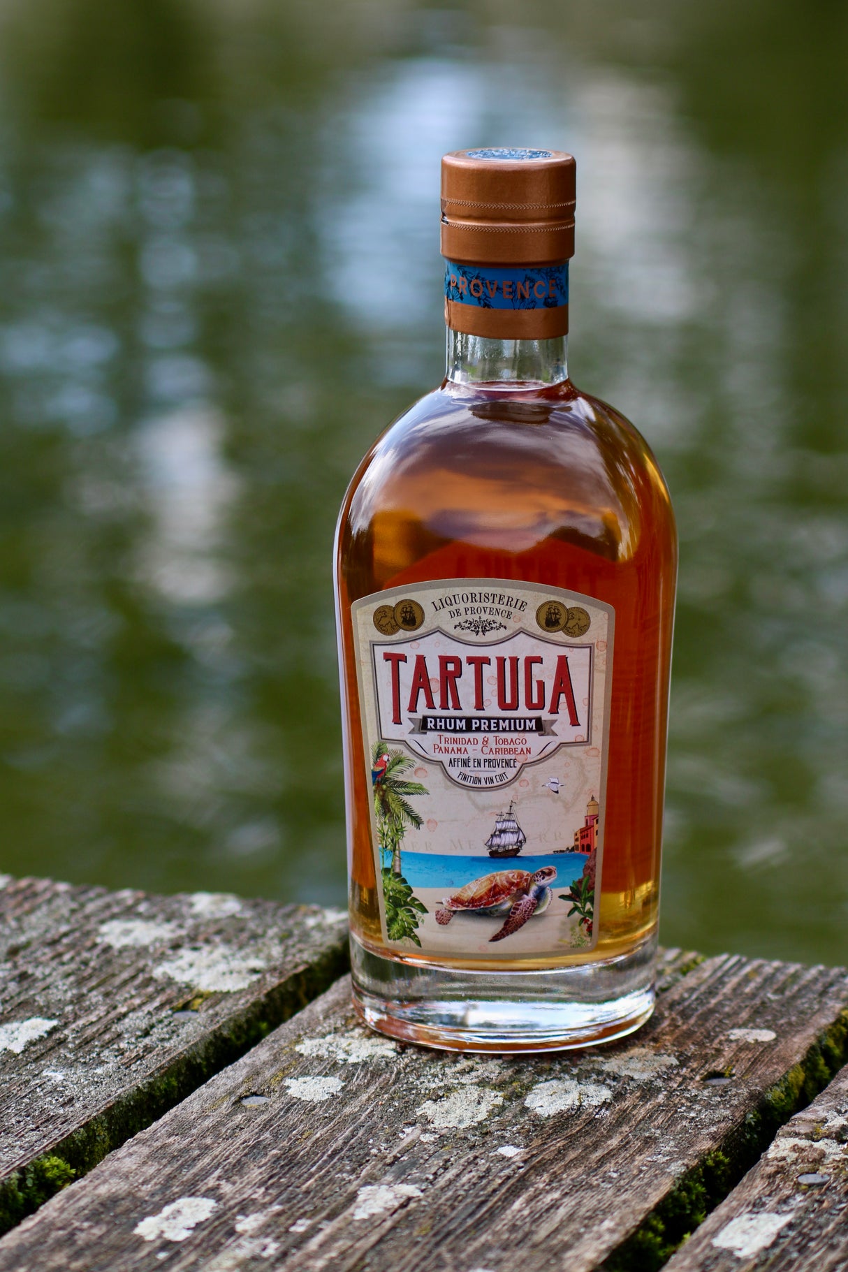 Tartuga Rumflasche auf verwittertem Holzbrett mit See im Hintergrund und maritimem Etikett
