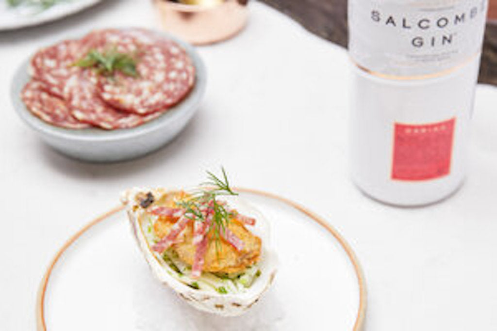 Salcombe Gin Daring mit Serviervorschlag: Gericht mit Garnitur aus Dill, daneben Schale mit Wurstscheiben, elegant aufgedeckt.