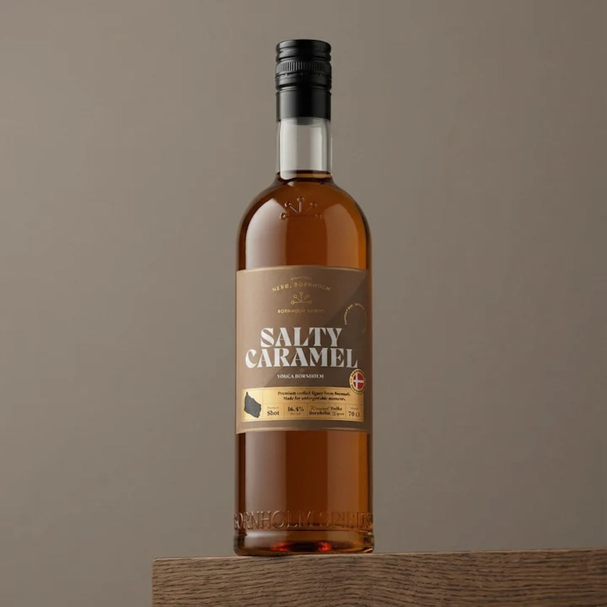Bornholm Salty Caramel Shot Flasche auf Holzoberfläche mit beigem Hintergrund und schwarzem Verschluss