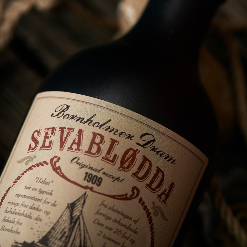 Nahaufnahme des Bornholmer Dram Sevablødda Etiketts mit Originalrezept von 1909, in rustikalem Stil mit maritimen Elementen.