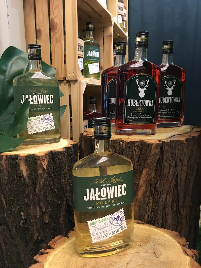 Jalowiec Polski Wacholder-Wodka und Hubertówka-Flaschen auf Holzstämmen und in Holzkisten ausgestellt.