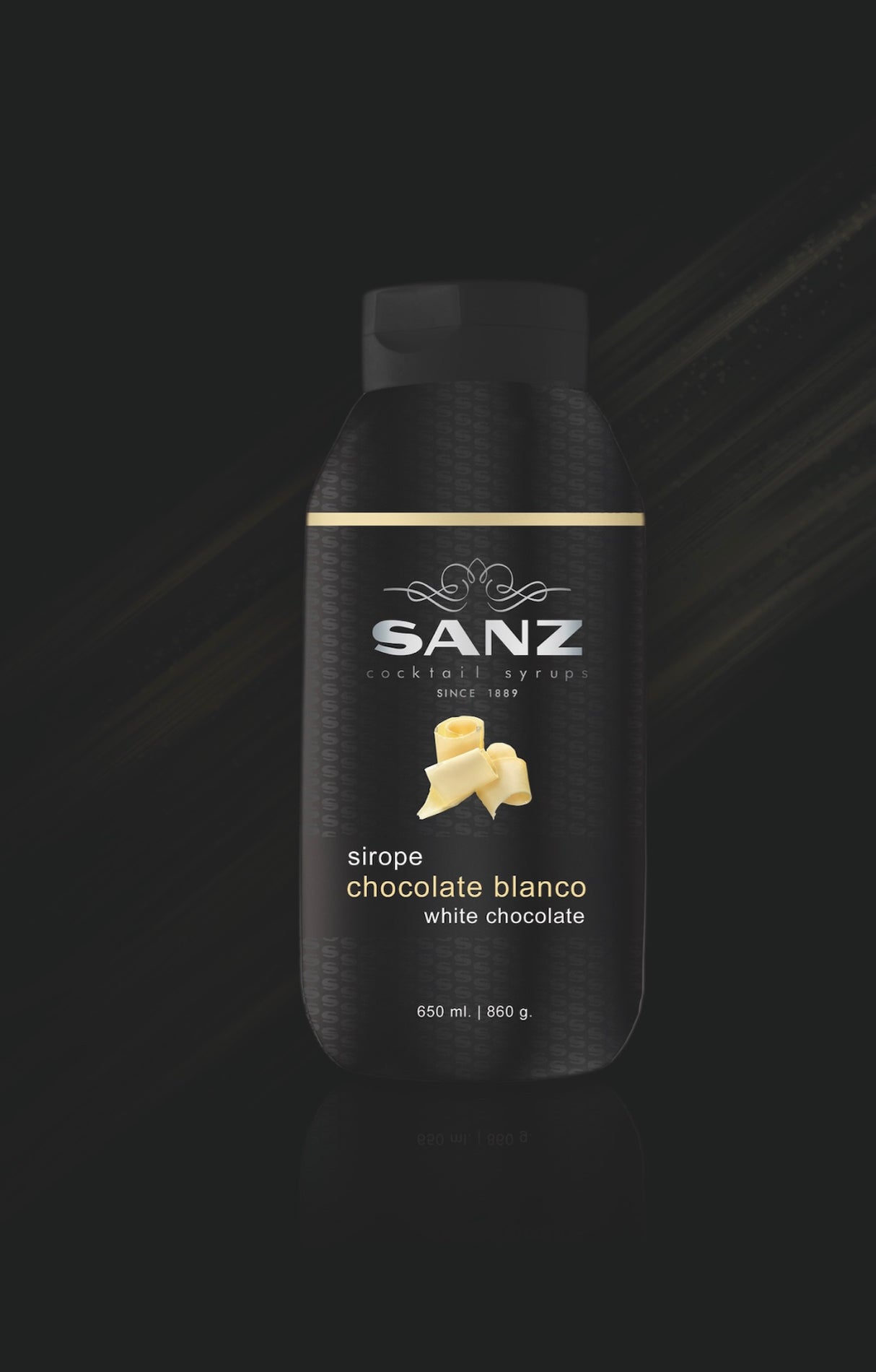 Flasche Sanz Sirup Weiße Schokolade, schwarze Verpackung mit goldener Linie und Schokoladenraspeln auf dunklem Hintergrund.
