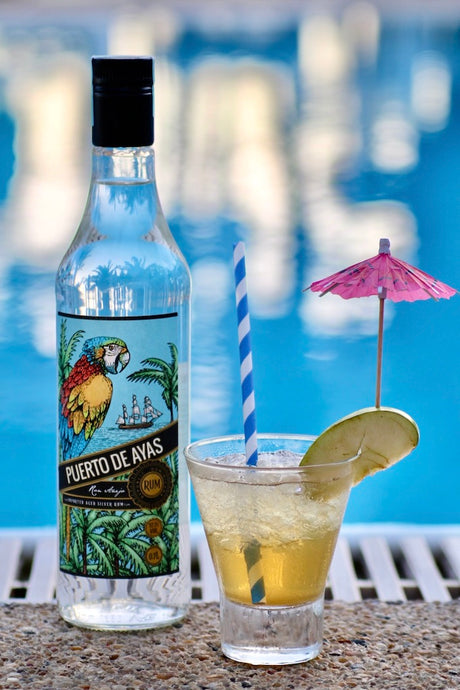 Rum-Apfel-Blend Cocktail mit Puerto de Ayas Rum, Apfelscheibe, Schirmchen und Strohhalm am Pool