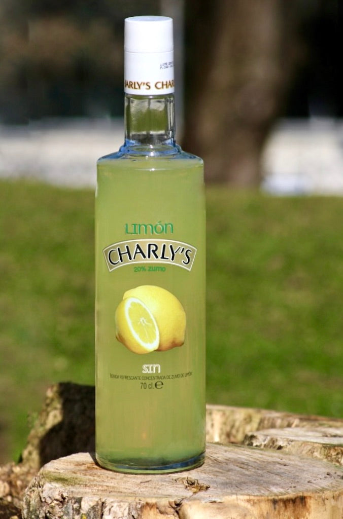 Flasche Charly's Limón, alkoholfreie Likör-Alternative mit 20 % Zitronensaft, fotografiert draußen auf einem Baumstumpf.