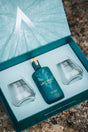 Geöffnete Arduenna Geschenkbox mit Bio Gin und zwei Gläsern im türkisfarbenen Inlay auf Naturstein.