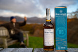 Flasche Bad na h-Achlaise Tuscan Oak Highland Single Malt Scotch Whisky mit Geschenkbox, im Hintergrund eine malerische Landschaft.