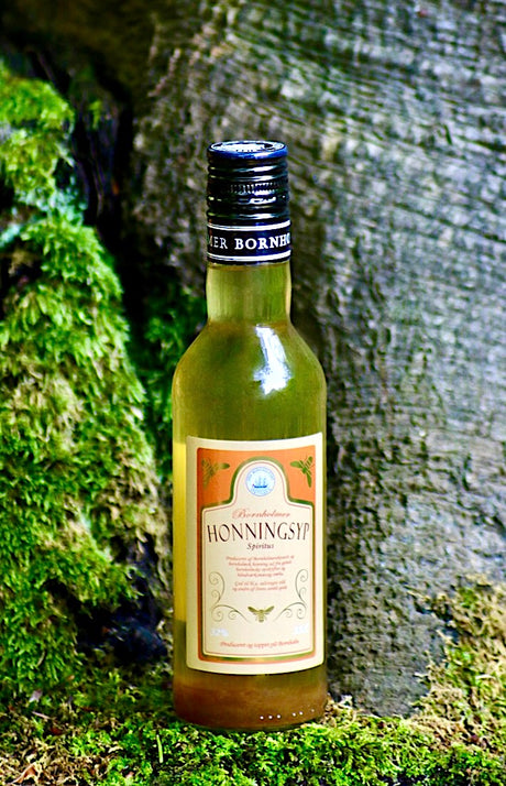 Flasche Bornholmer Honningsyp Honig-Schnaps, präsentiert in einer natürlichen Umgebung mit Moos und Holz.