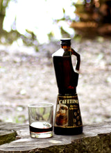 Cafetino Kaffeelikör in Kaffeekocher Flasche mit Glas auf Holz vor hellem Naturhintergrund