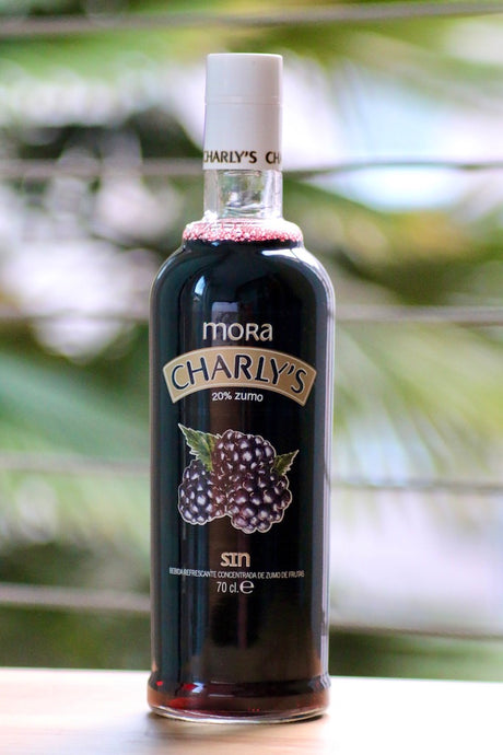 Charly's Mora alkoholfreies Brombeergetränk, 70 cl, schwarzes Etikett mit Brombeeren, 20% Fruchtgehalt, vor grünem Hintergrund.