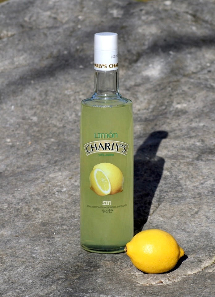 Charly's Limón alkoholfreie Likör-Alternative, 70 cl Flasche, auf grauem Stein platziert, begleitet von einer frischen Zitrone.