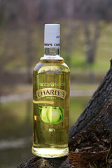 Flasche Charly's Grüner Apfel, alkoholfreies Getränk mit 35 % Apfelsaft, vor einem unscharfen, natürlichen Hintergrund platziert.