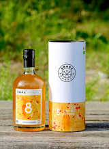 Flasche und Geschenkbox Bio-Schnaps Bornholm, Chili und Honig, auf Holzoberfläche vor unscharfem, grünem Hintergrund.