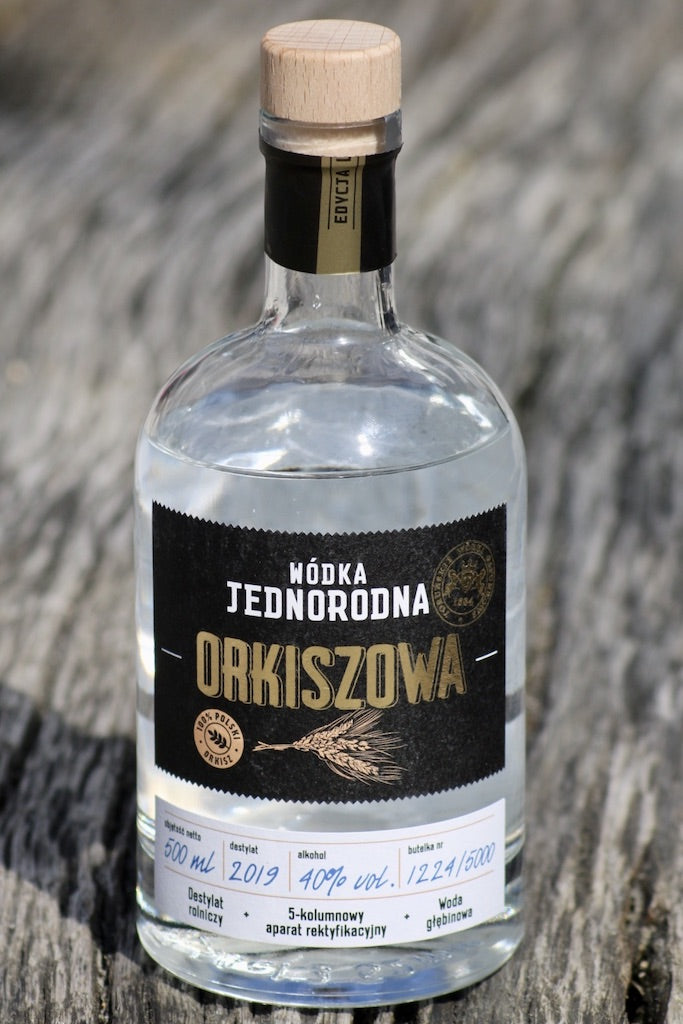 Flasche Wódka Jednorodna Orkiszowa, 500 ml, 40 % Vol., mit Holzverschluss, stehend auf einer Holzoberfläche.