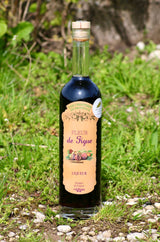 Flasche Fleur de Figue Likör, 500 ml, stehend auf einer Wiese, mit naturfarbenem Etikett und Holzverschluss, umgeben von grüner Vegetation.