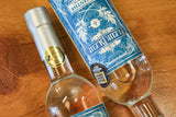 Zwei Fleur Bleue Absinth Flaschen mit blauem Etikett und Medaillen auf Holztisch