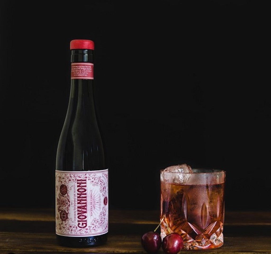 Giovannoni Rosso Flasche auf Holztisch mit Kirsch Negroni Cocktail