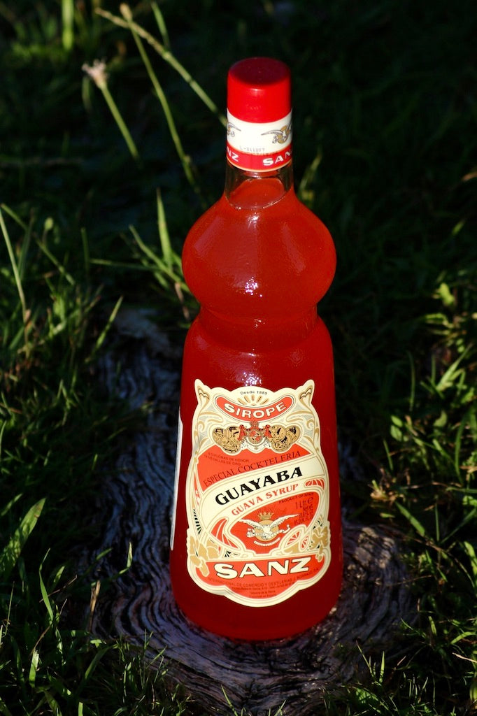 Flasche Guavensirup Sanz auf einem Baumstumpf im Gras.