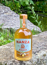 Hanza Ginger Ingwerlikör auf einem Felsen am See, Flasche mit Ingwermotiv und Segelschiff auf dem Etikett.