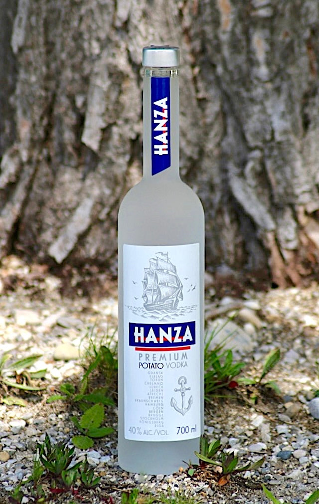 Hanza Premium Kartoffel Vodka Flasche, 700 ml, im Freien vor einem Baum platziert, mit Gras und Steinen im Vordergrund.