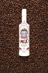 MEX Crema de Café con Tequila Likör Flasche mit Catrina-Etikett, liegend auf gerösteten Kaffeebohnen.