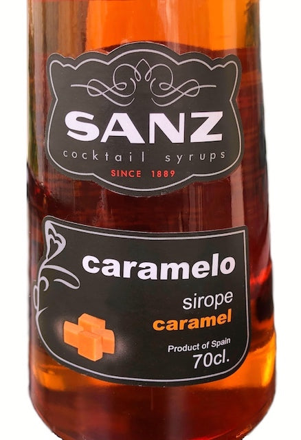 Nahaufnahme des Etiketts der Sanz Karamellsirup 700 ml Flasche mit Markenlogo und Produktinformationen auf schwarzem Hintergrund.