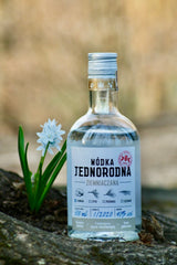 Wodka Jednorodna Ziemniaczana, polnischer Kartoffelwodka, 500 ml, 40 % vol, Flasche auf einem Felsen mit Blume im Hintergrund