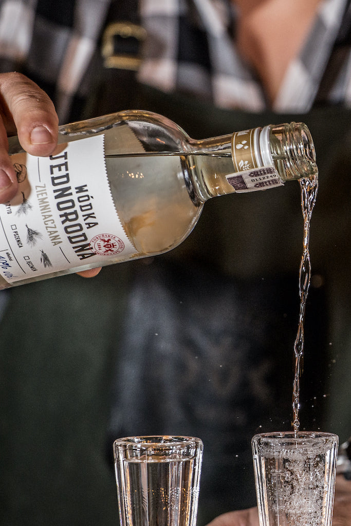 Eine Flasche Wodka Jednorodna Ziemniaczana wird in zwei Gläser eingeschenkt.