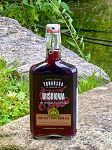 Toruńska Wiśniowa Kirschlikör mit Bügelverschluss auf einem Felsen am See, Flasche mit Kirschmotiv auf dem Etikett.