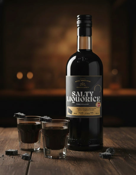 Bornholm-Salty-Liquorice-Flasche auf Holztisch mit zwei dunklen Shots und Lakritzstücken in warmer, unscharfer Bar-Umgebung.