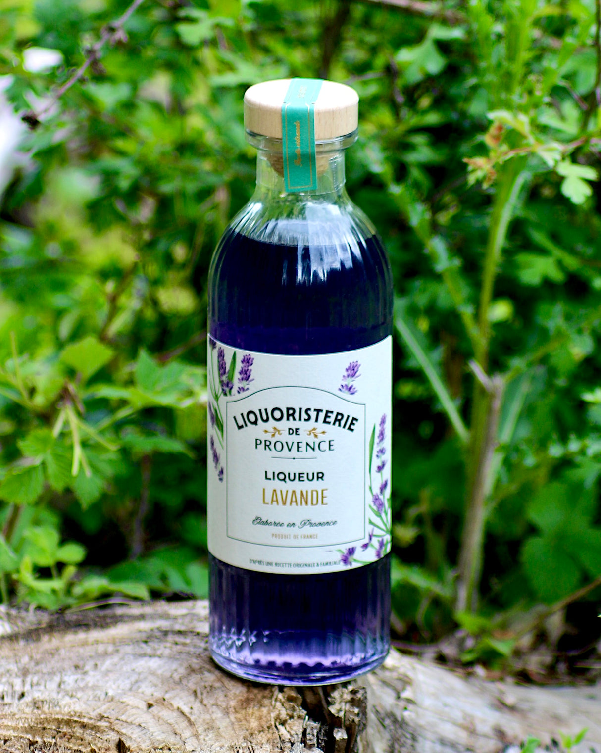 Lavendellikör Liquoristerie de Provence Flasche auf Holz vor grünem Naturhintergrund