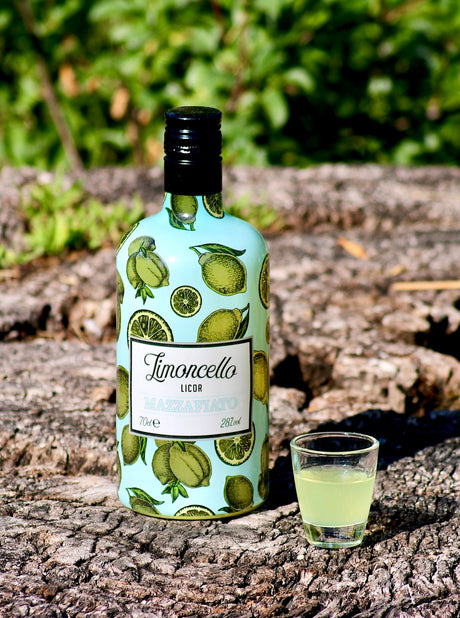 Limoncello Mazzafiato Flasche mit Shotglas auf Baumrinde vor grünem Hintergrund