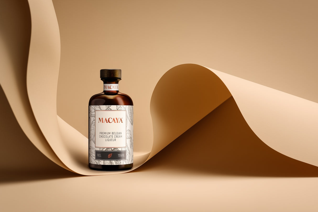 Macaya Schokoladenlikör mit Sahne auf beigefarbenem Hintergrund, dekoriert mit geschwungenem Papier