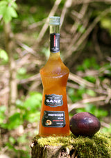 Flasche Sanz Maracuyá Sirup 70cl mit schwarzem Etikett „maracuyá sirope passion fruit“ auf einem Baumstumpf, daneben eine Passionsfrucht.