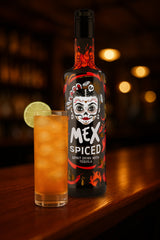 Mex Spiced Spirituose mit Tequila und Chili in schwarzer Flasche, daneben Highball mit Eis und Limettenscheibe