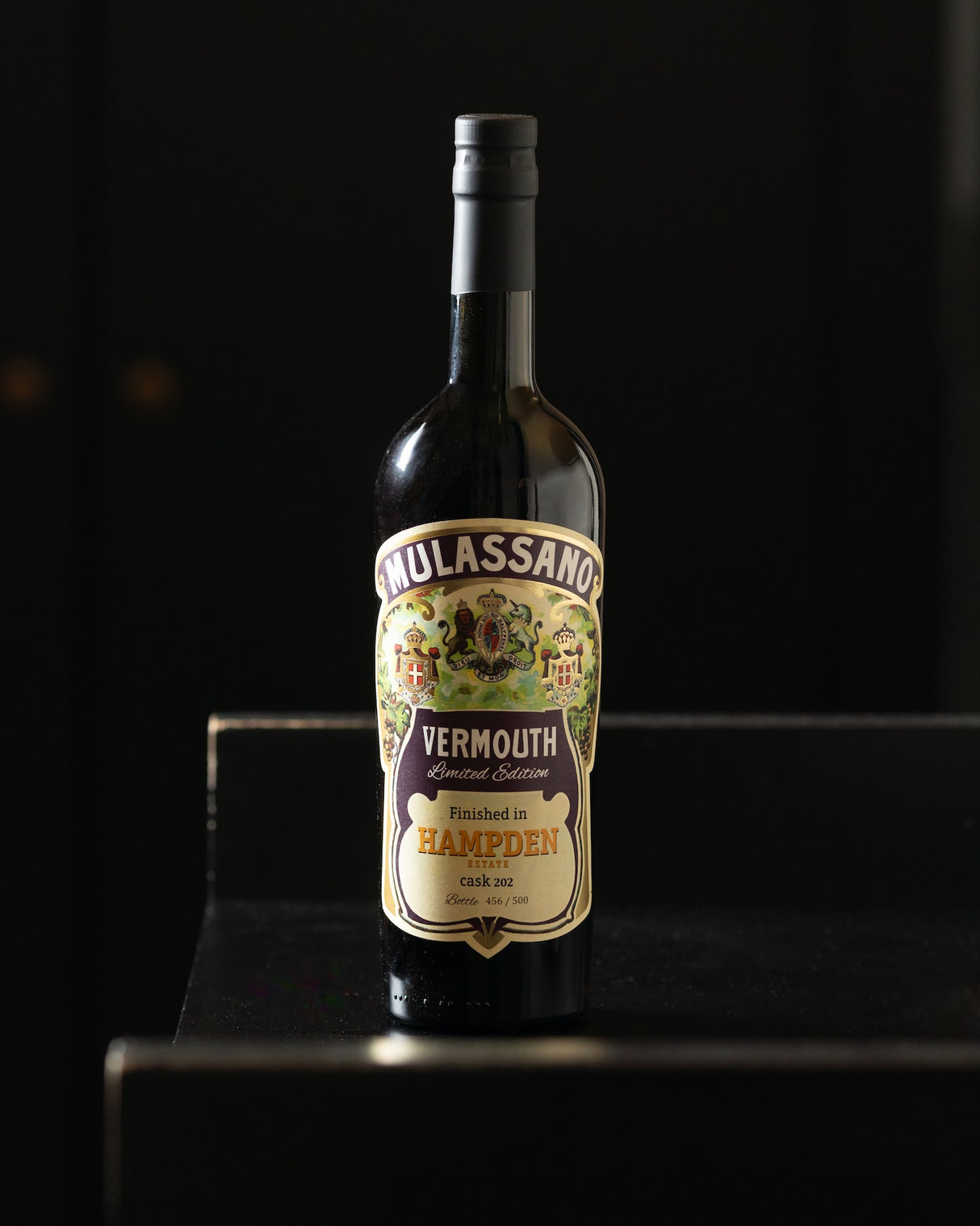 Flasche Vermouth Mulassano vor schwarzem Hintergrund auf dunkler Kante. Etikett: Finished in Hampden Estate cask 202.