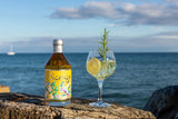 Nerses gelber Gin & Tonic mit Rosmarinzweige und Zitrone am Strand in Barcelona