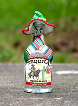 Panchitos Tequila Blanco Flasche mit Sombrero und Poncho auf grauer Fläche vor grünem Hintergrund
