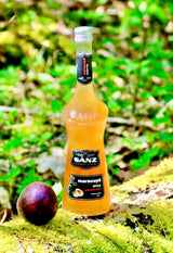 Flasche Sanz Maracuyá Sirup 70cl mit schwarzem Etikett „maracuyá sirope passion fruit“ auf Moos, daneben eine Passionsfrucht.